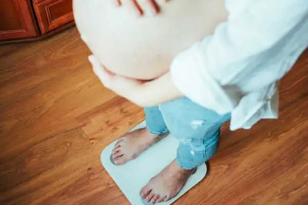 Image of woman weighing herself and experiencing weight gain through pregnancy Maldon
